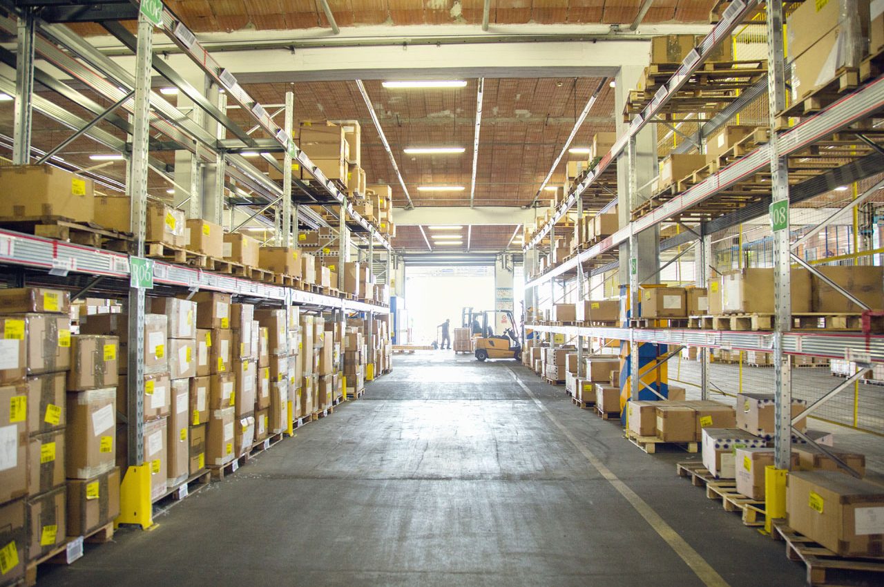 Forklift trucks and drivers working in distribution warehouse aisle